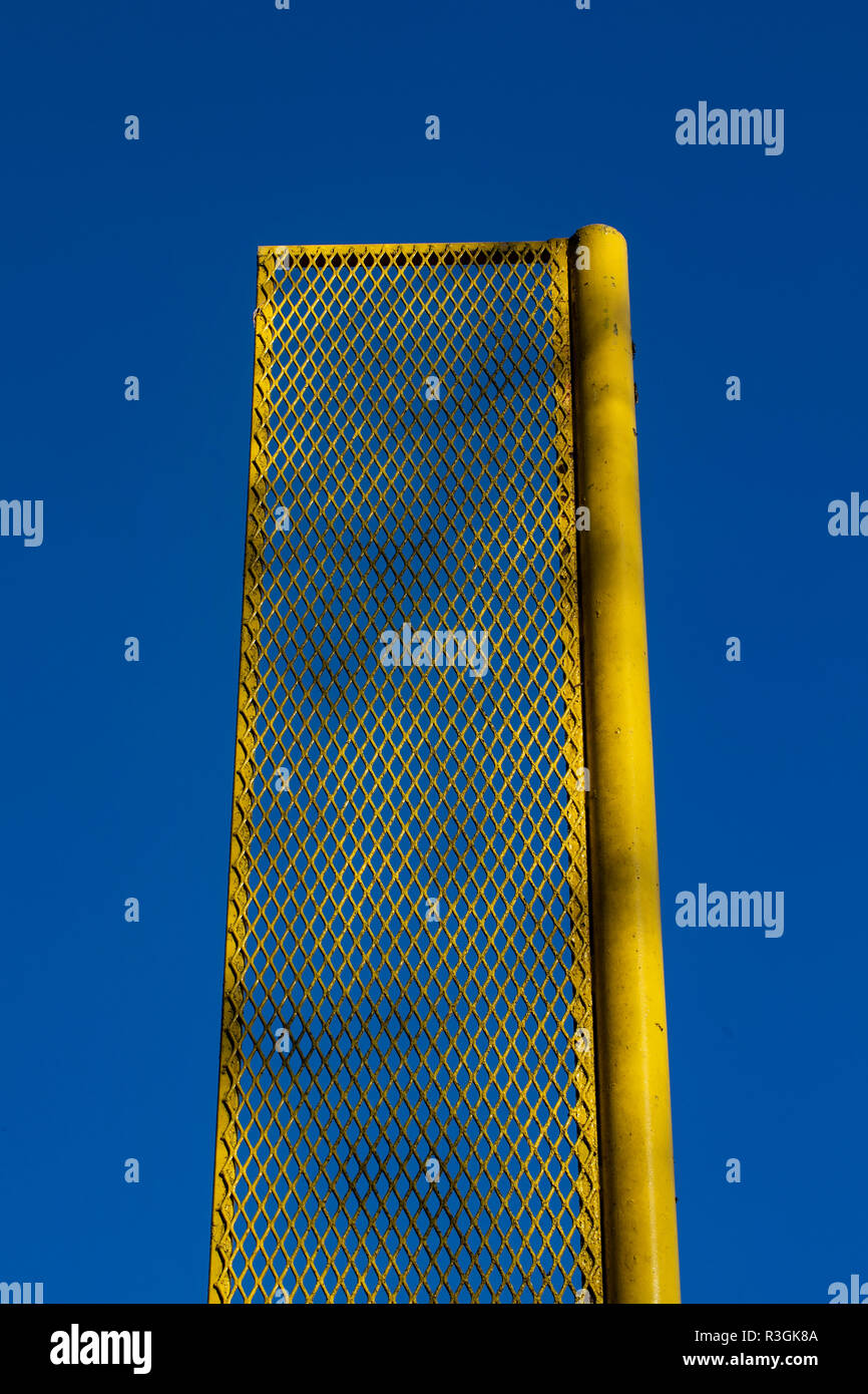 Giallo fallo polo ricreativo sul campo da baseball è incorniciato contro un profondo cielo blu. Foto Stock