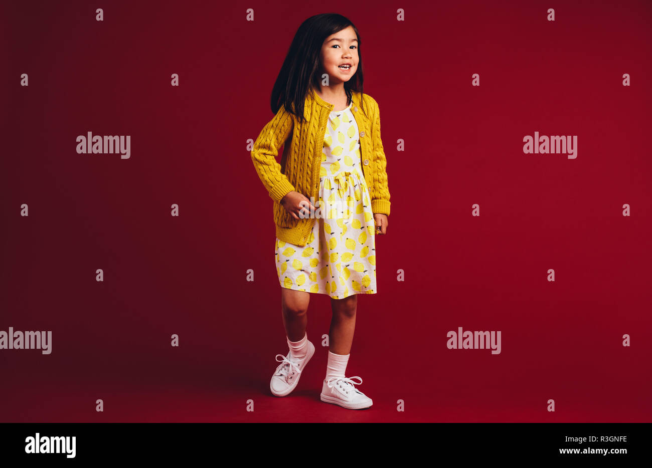 A piena lunghezza Ritratto di un sorridente ragazzo asiatico in piedi contro uno sfondo di colore rosso. Foto Stock