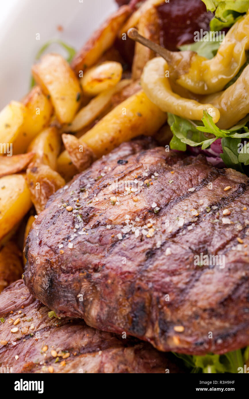Enorme barbecue piastra con misto di carne e bistecche su insalata Foto Stock