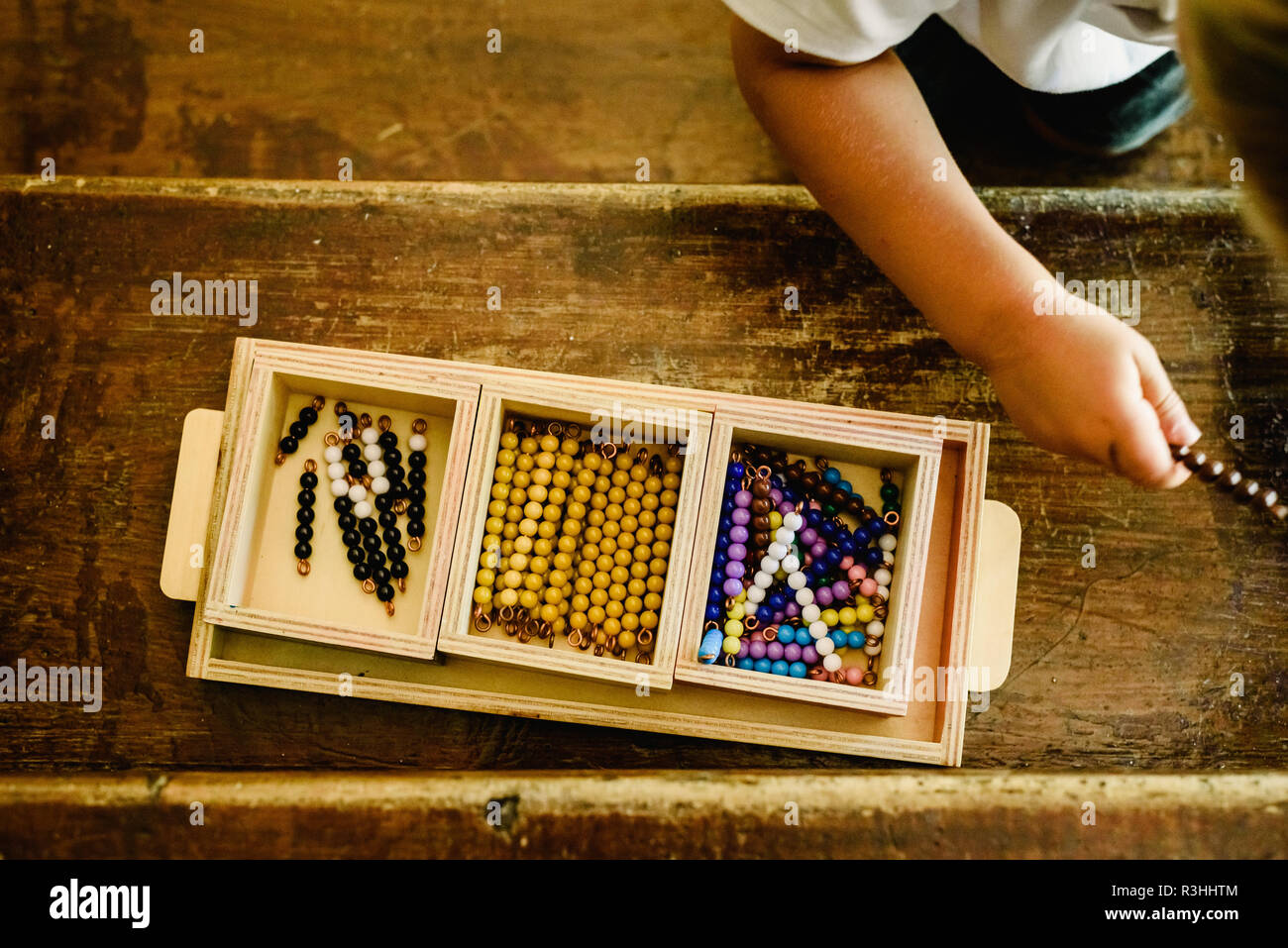 Le mani di un bambino la manipolazione di materiali didattici per imparare a contare in una classe Montessori. Foto Stock