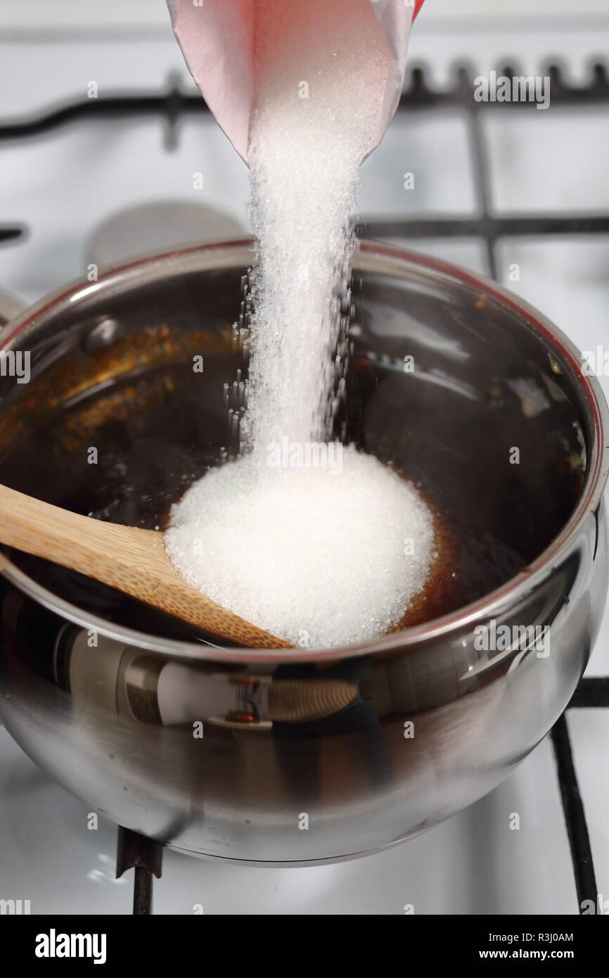 Aggiungere lo zucchero in una miscela di acqua e zucchero caramellato. Realizzazione di sciroppo dorato serie. Foto Stock
