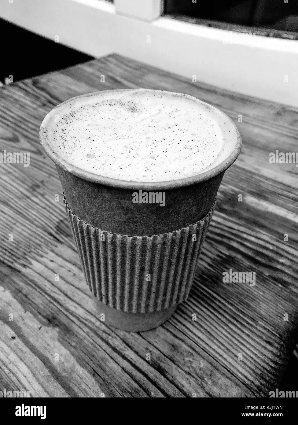 Foto in bianco e nero. Cappuccino in un bicchiere di carta. Street coffee shop Foto Stock