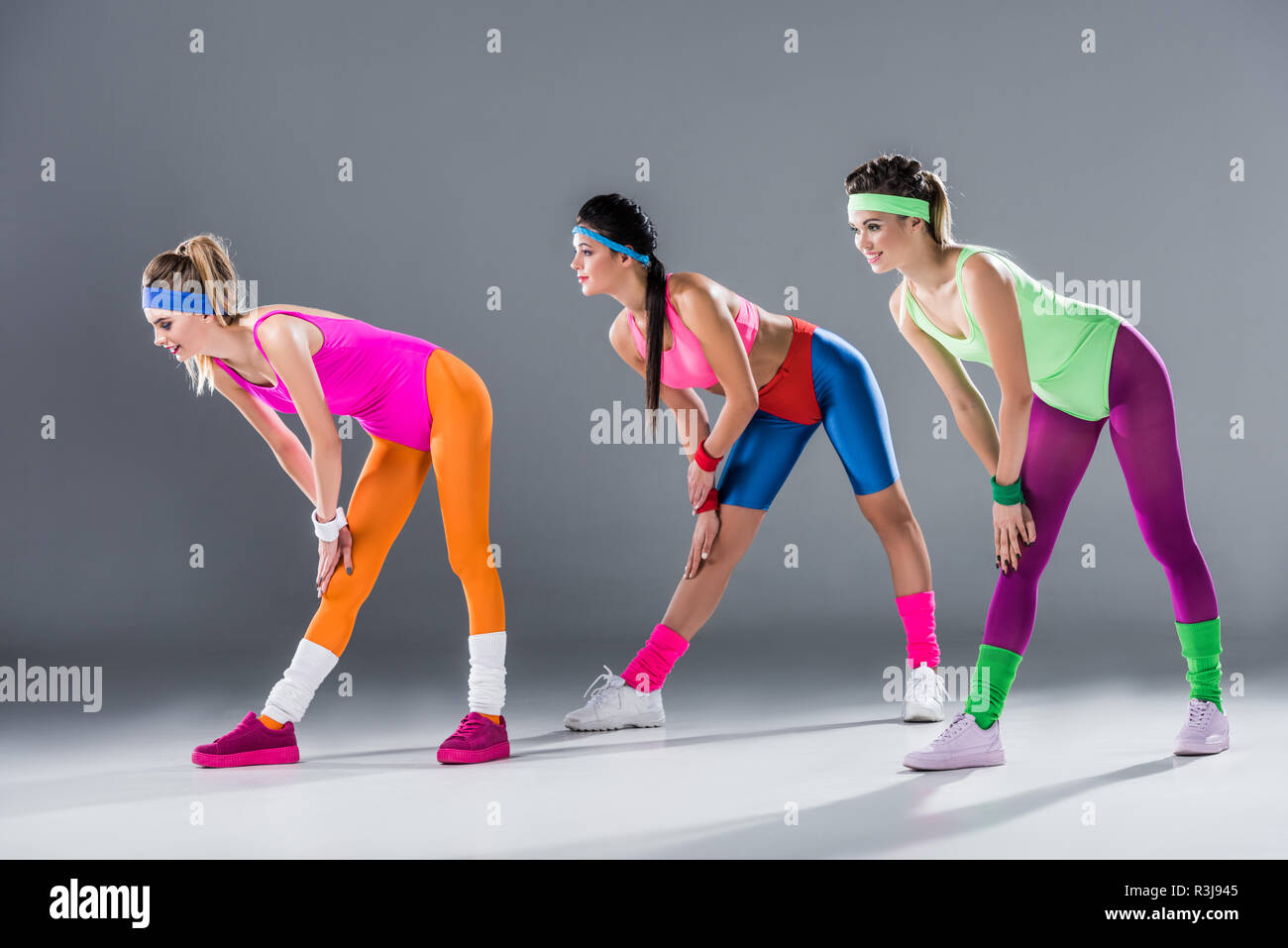 Belle ragazze sportivo in 80s style sportswear esercitare insieme su grigio Foto Stock