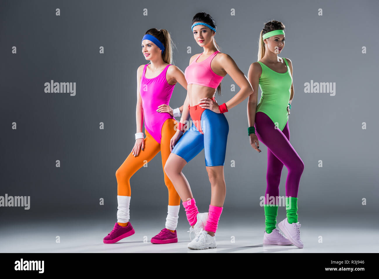 Attraente ragazze sportivo in 80s style sportswear in posa insieme su grigio Foto Stock