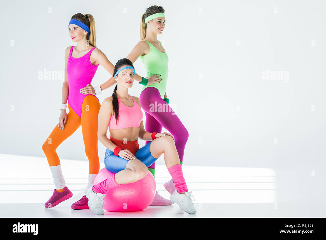 Athletic giovani donne in 80s style sportswear in posa insieme su grigio Foto Stock