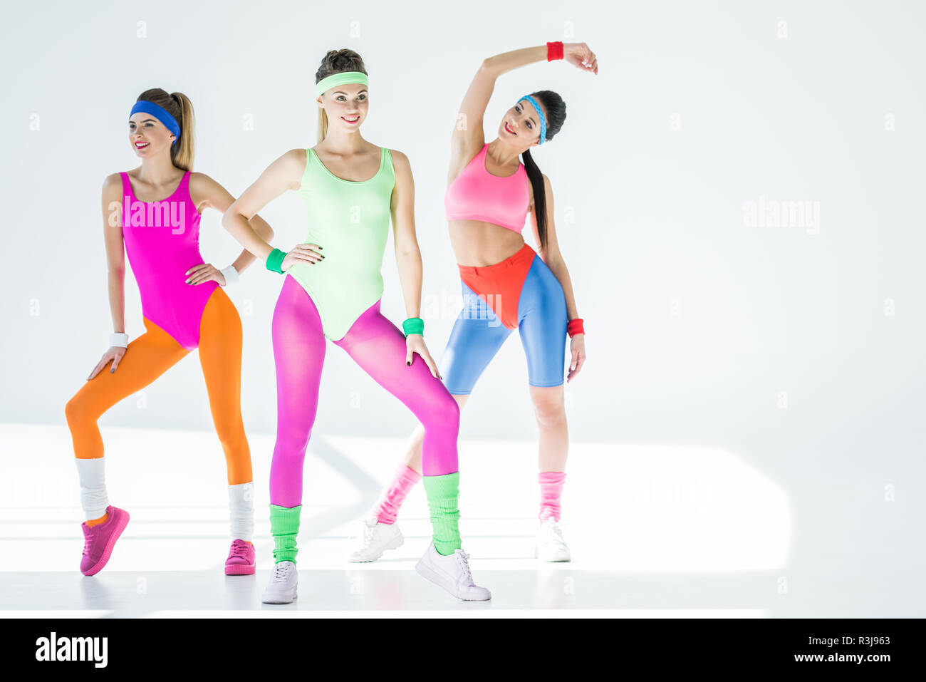 Belle ragazze atletiche in 80s style sportswear esercitare insieme su grigio Foto Stock