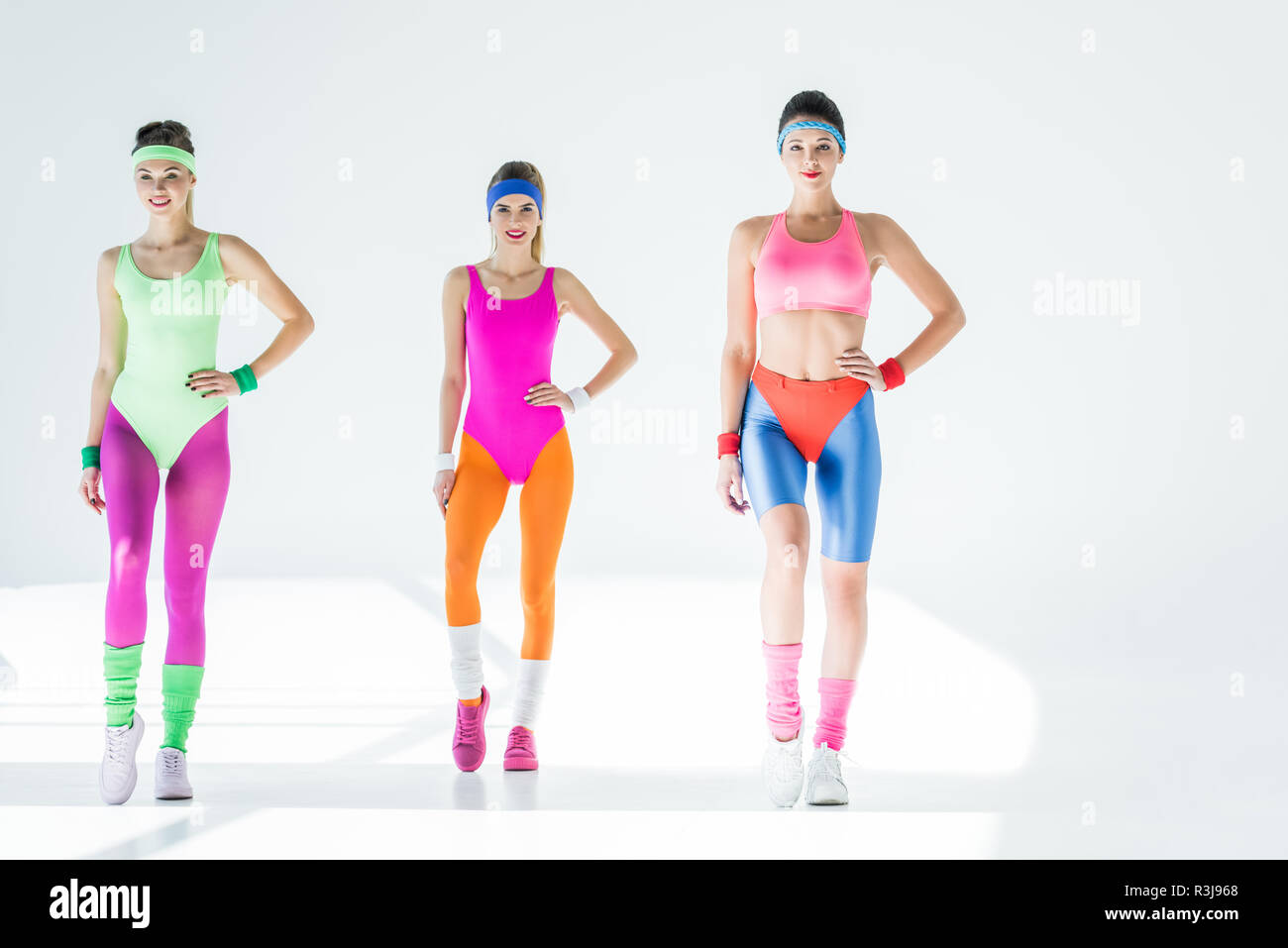 Sorridenti ragazze sportivo esercizio di aerobica allenamento su grigio Foto Stock