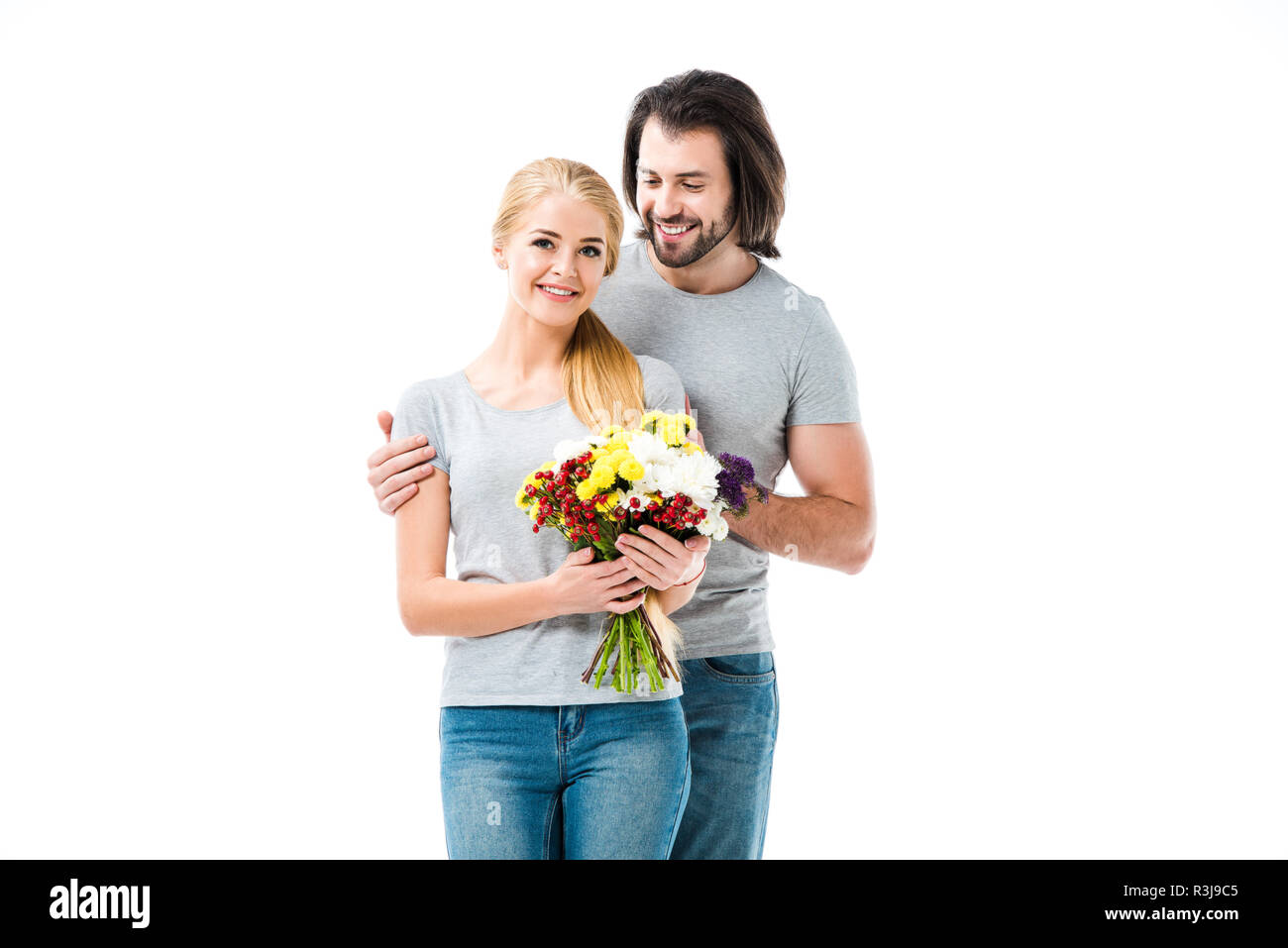 Coppia splendida abbracciando mentre donna azienda fiori isolati su bianco Foto Stock