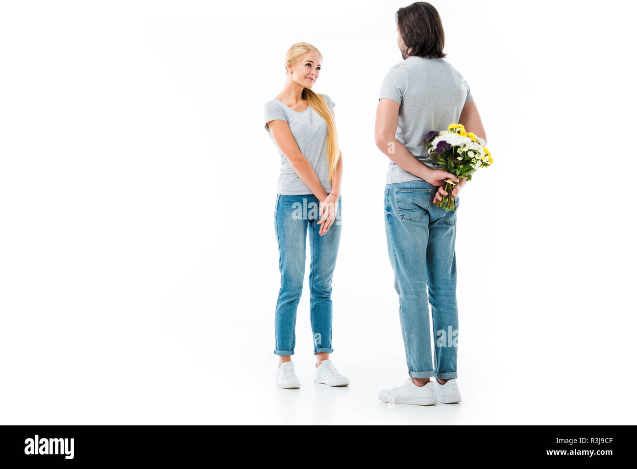 Coppia splendida guardando ogni altro uomo con fiori dietro la schiena isolato su bianco Foto Stock