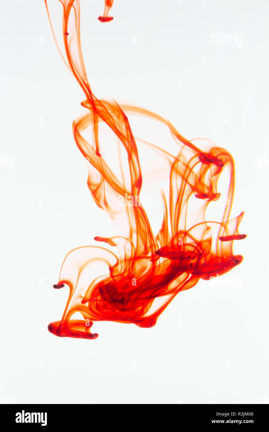 Colorante alimentare gocciolata in un bicchiere di acqua e disperdendo. Foto Stock