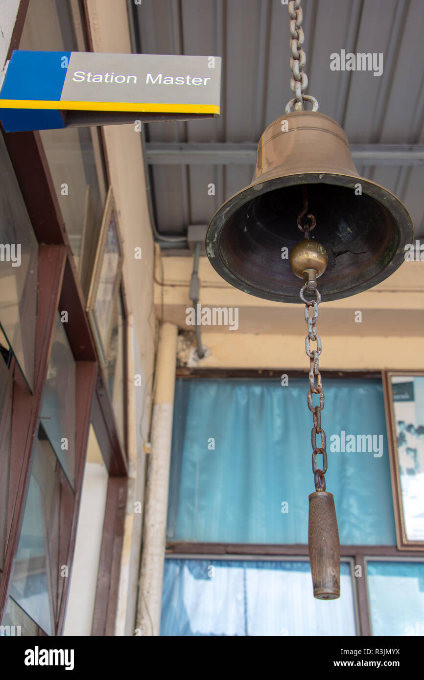 Closeup firmare la stazione master con un campanello d'oro in una stazione ferroviaria. Suono tradizionale segnalazione su piattaforma presso la stazione ferroviaria. Foto Stock