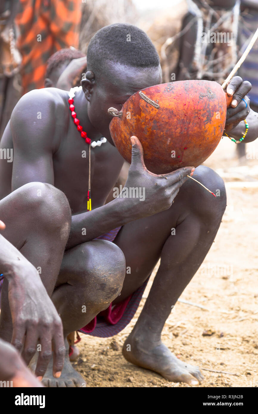Africa, Etiopia, sud della valle dell'Omo, Nyangatom tribù. Un uomo Nyangatom bevande la miscela di sangue e di latte nella calabash. Foto Stock