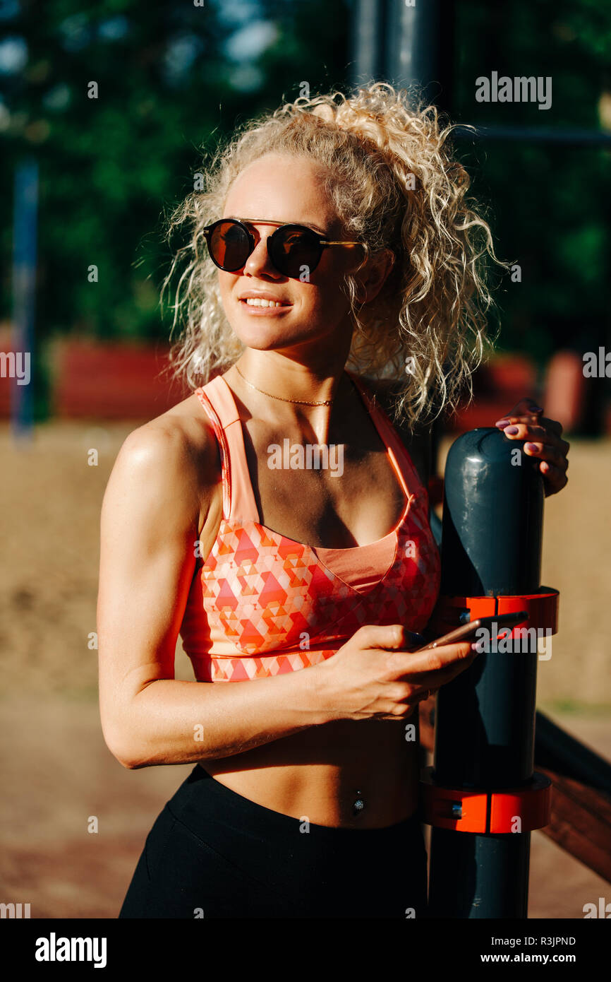 Foto di sport donna che indossa gli occhiali da sole tenendo il telefono in  mano Foto stock - Alamy