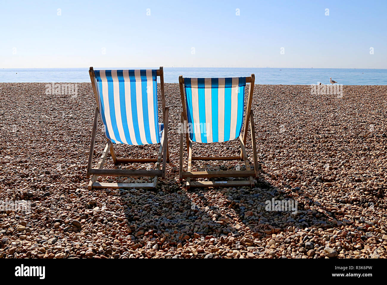 Vuoto di due sdraio e un gabbiano sulla Spiaggia di Brighton. Regno Unito Foto Stock