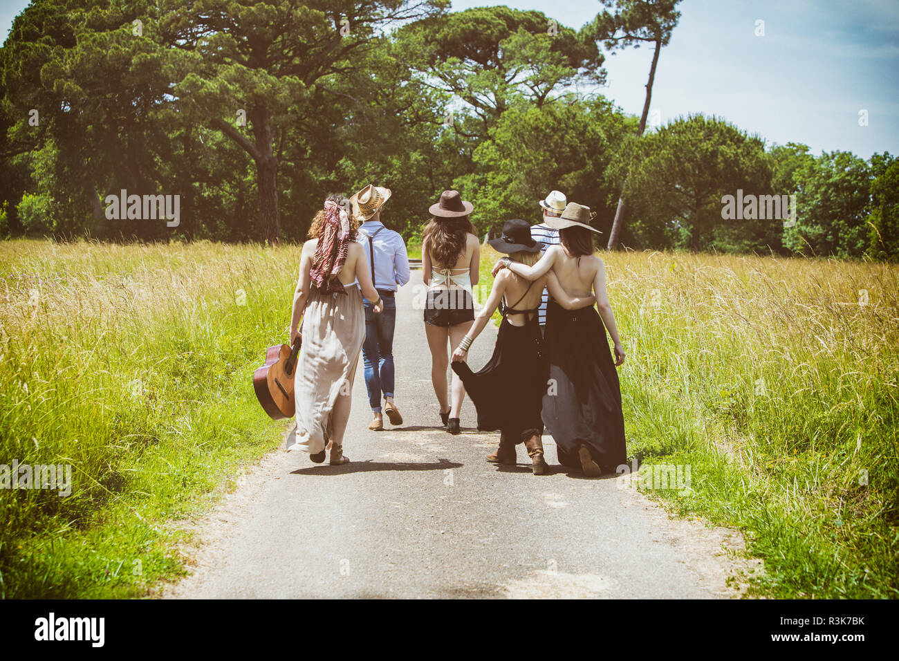 Gruppo di giovani hipster vista frontale, camminando sulla strada di campagna Foto Stock