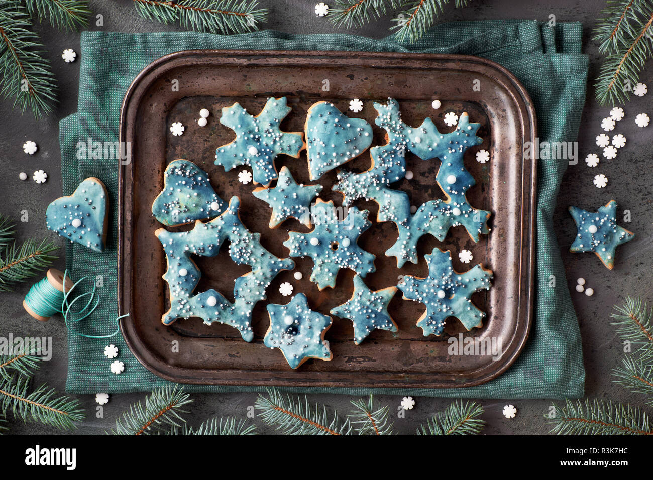 Vassoio di biscotti di Natale nelle forme di fiocchi di neve, stelle e sente di metallo sul vassoio da forno, piatto giaceva su sfondo scuro con ramoscelli di abete e cospargere di zucchero Foto Stock