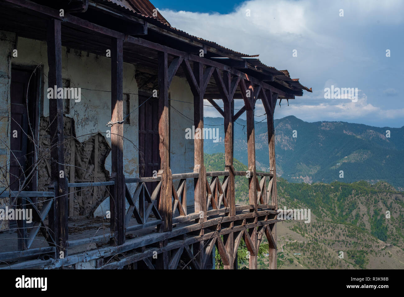 Un vecchio fatiscente struttura di legno casa tradizionale in Shimla (Simla) con il foothills dell'Himalaya in background in Himachal Pradesh Foto Stock