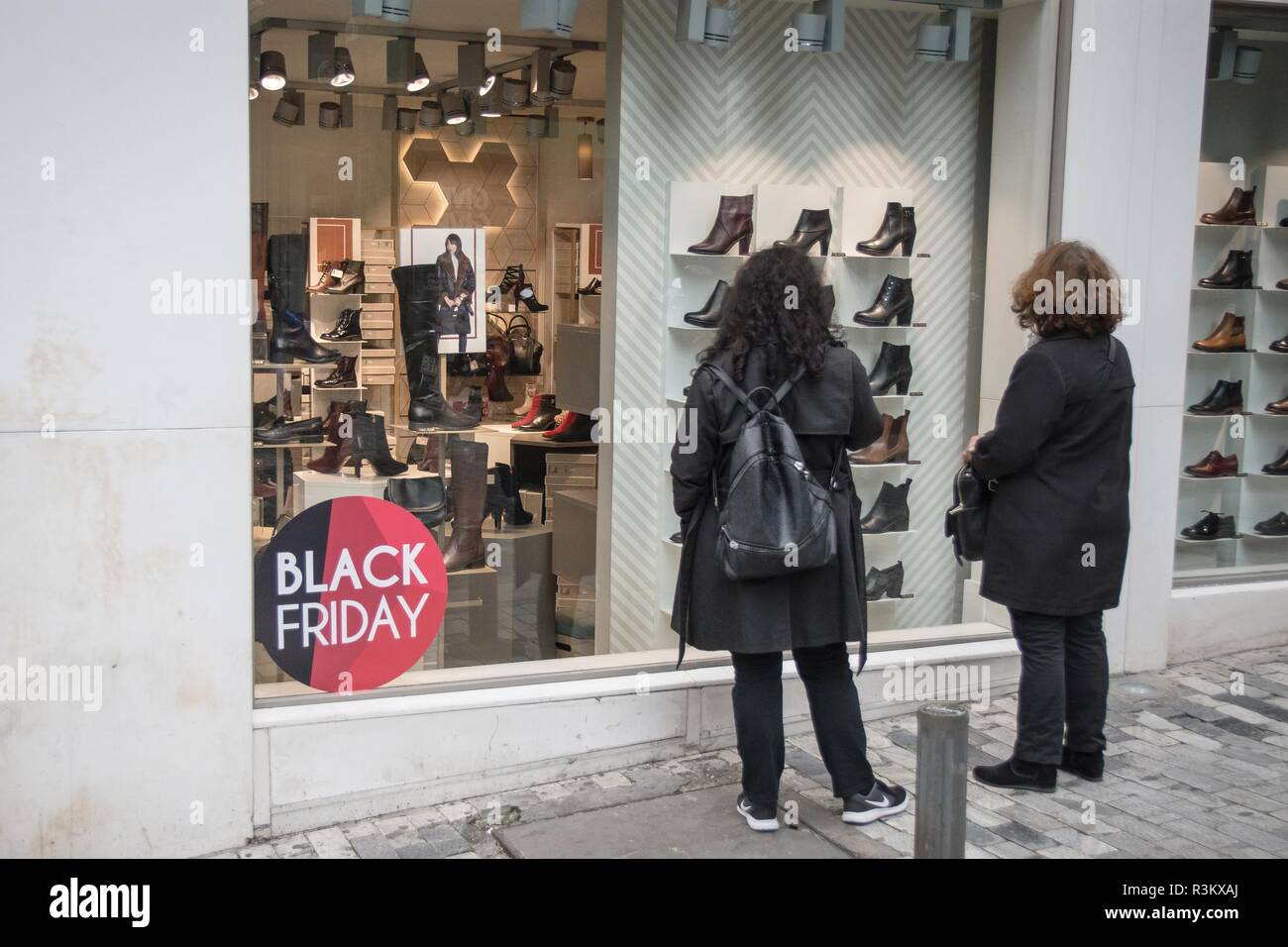 Atene, Grecia. 23 Nov 2018. Le donne sono viste in piedi accanto alla vetrina con il Black Friday sconti. Migliaia di persone hanno invaso il centro di Atene al negozio, dovuta al Venerdì nero sconti. Credito: SOPA Immagini limitata/Alamy Live News Foto Stock