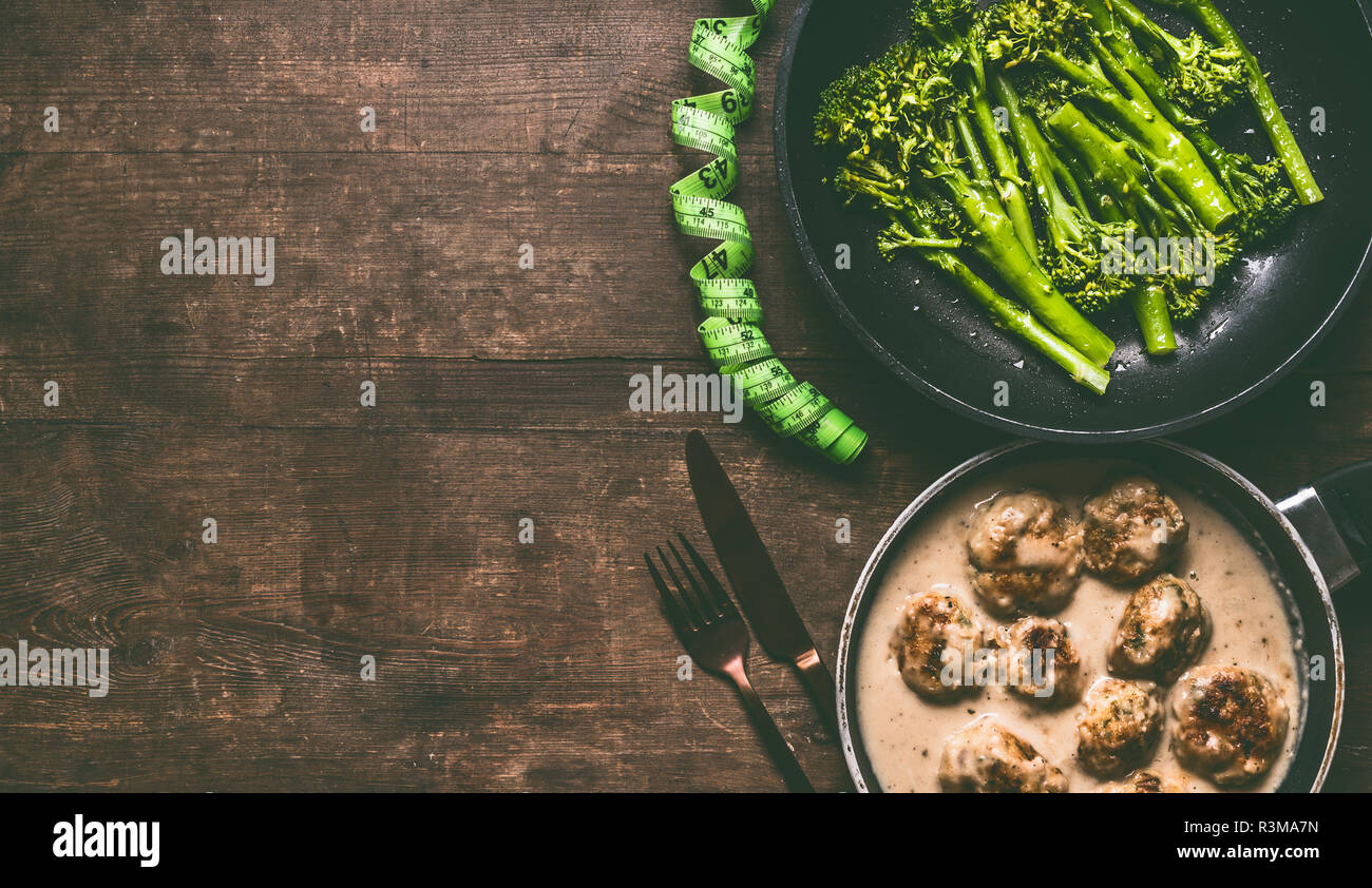 Low Carb dieta pasto con polpettine di carne, broccoli sbollentati nel recipiente di cottura, posate e misurare il nastro sul tavolo di legno sfondo, vista dall'alto con spazio di copia Foto Stock