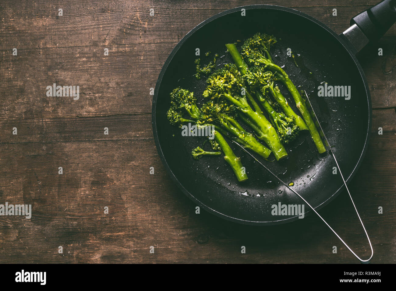 Broccoli sbollentati in nero brasiera su sfondo di legno, vista dall'alto con copia spazio. Orizzontale. Vegetariano una sana perdita di peso la dieta alimenti Foto Stock