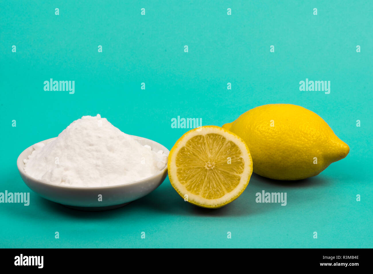 Limone e bicarbonato di sodio in un piattino isolato in neon blu. Foto Stock