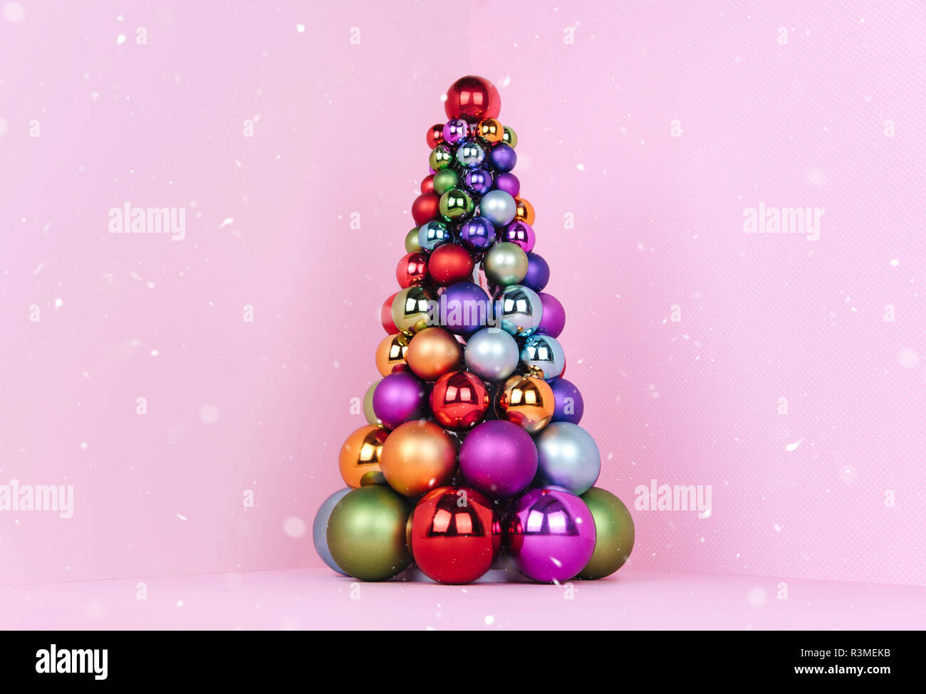 Albero di Natale fatto di decorazione a sfera su sfondo rosa. Foto Stock