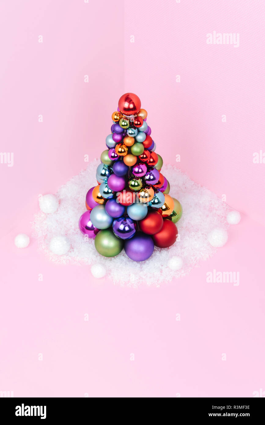 Albero di Natale fatto di decorazione a sfera su sfondo rosa. Foto Stock