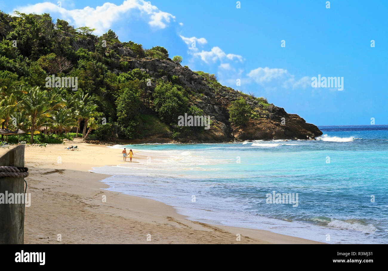 Antigua, Galley Bay. Giovane passeggiate lungo la spiaggia di sabbia Foto Stock