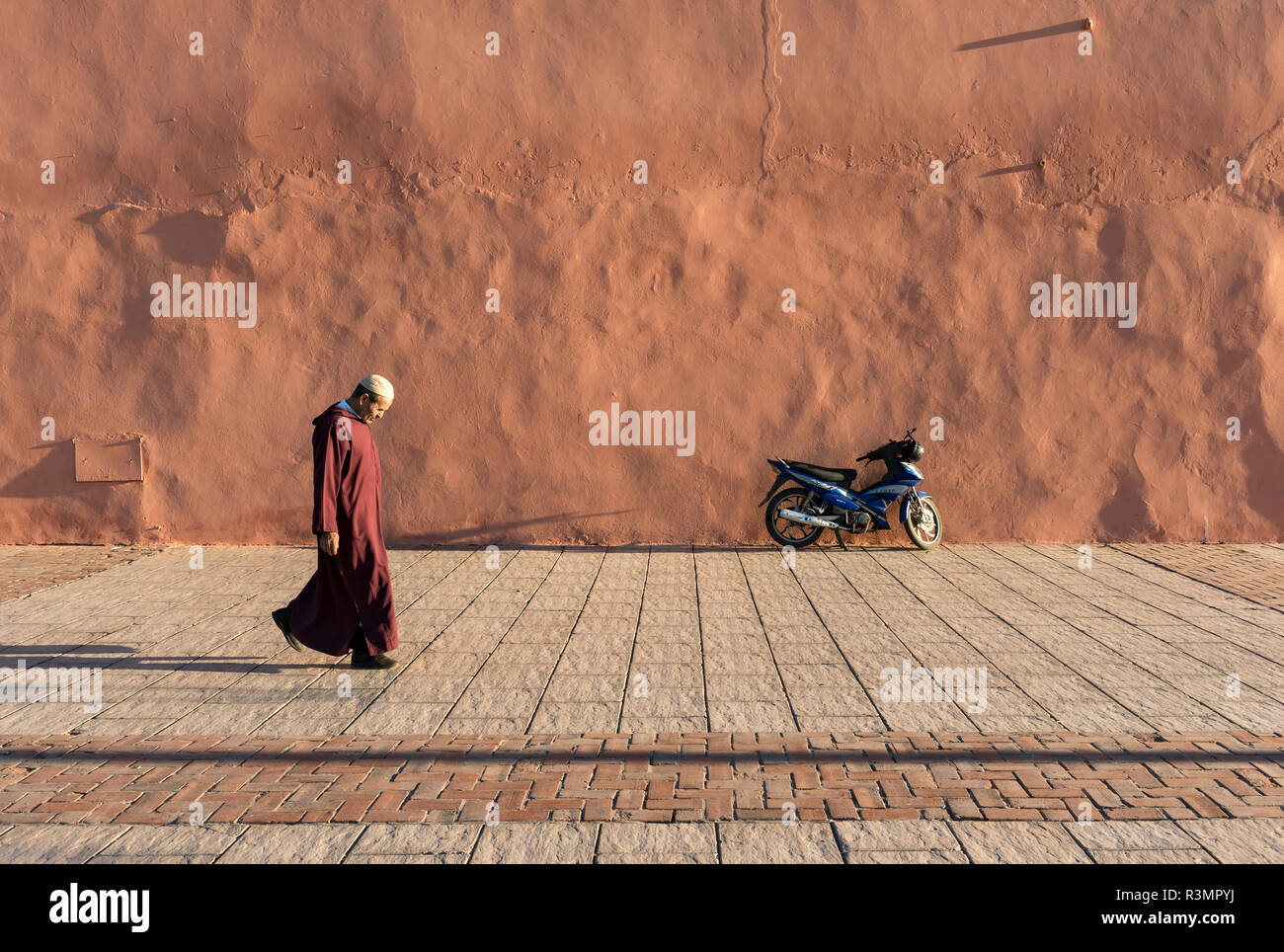 L'uomo cammina lungo rosso-arancione mura della città di Marrakech (Marrakech), Marocco Foto Stock