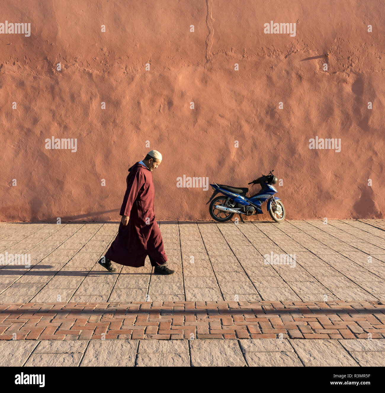 L'uomo cammina lungo rosso-arancione mura della città di Marrakech (Marrakech), Marocco Foto Stock