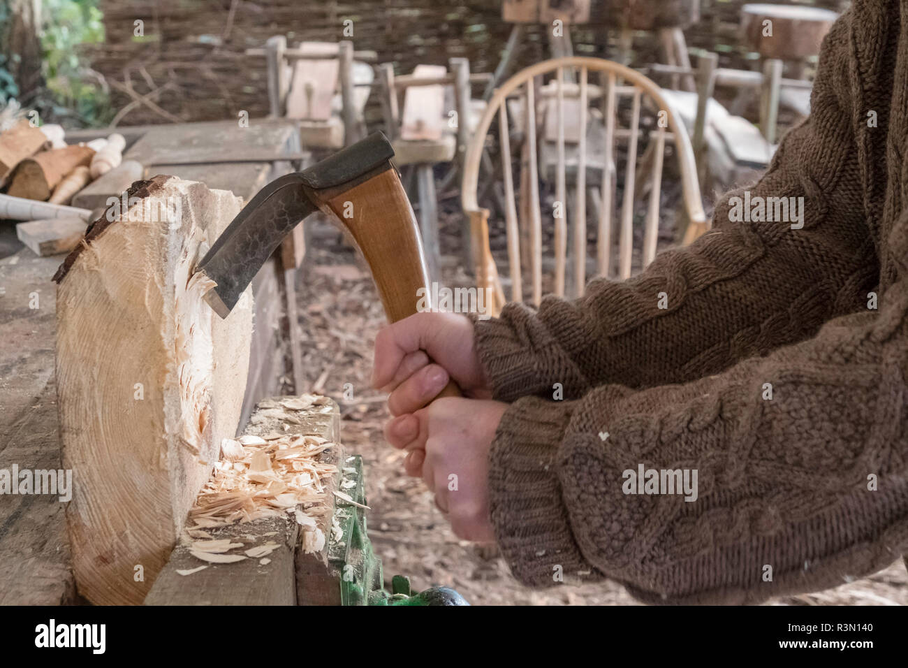 Usando una mano adze alla moda la sede per uno sgabello. Foto Stock