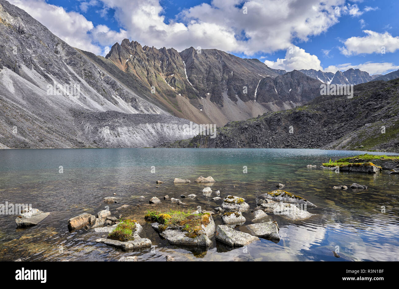 Frammenti di roccia ricoperte di erba e muschio in acqua di lago di montagna. Paesaggio di acqua nelle montagne della Siberia orientale Foto Stock