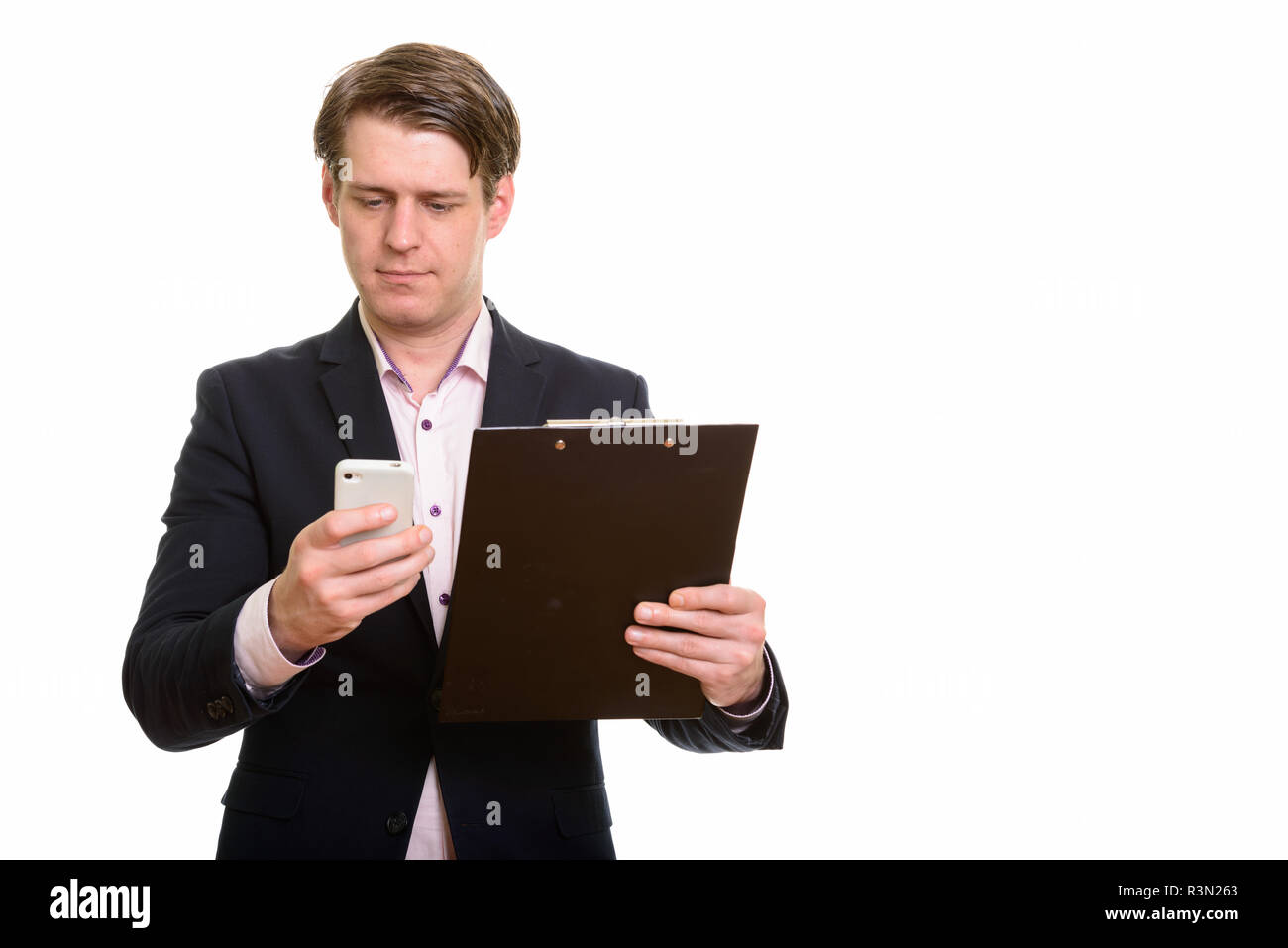 Bello imprenditore caucasico utilizzando il telefono cellulare mentre si tiene premuto Foto Stock