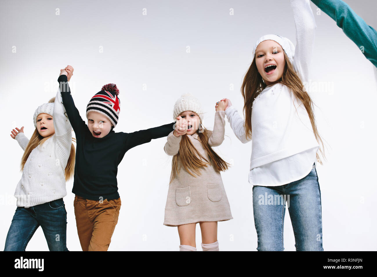 Un gruppo di bambini nella luminosa abbigliamento invernale, isolato su bianco studio. Moda, infanzia felice concetto emozioni Foto Stock