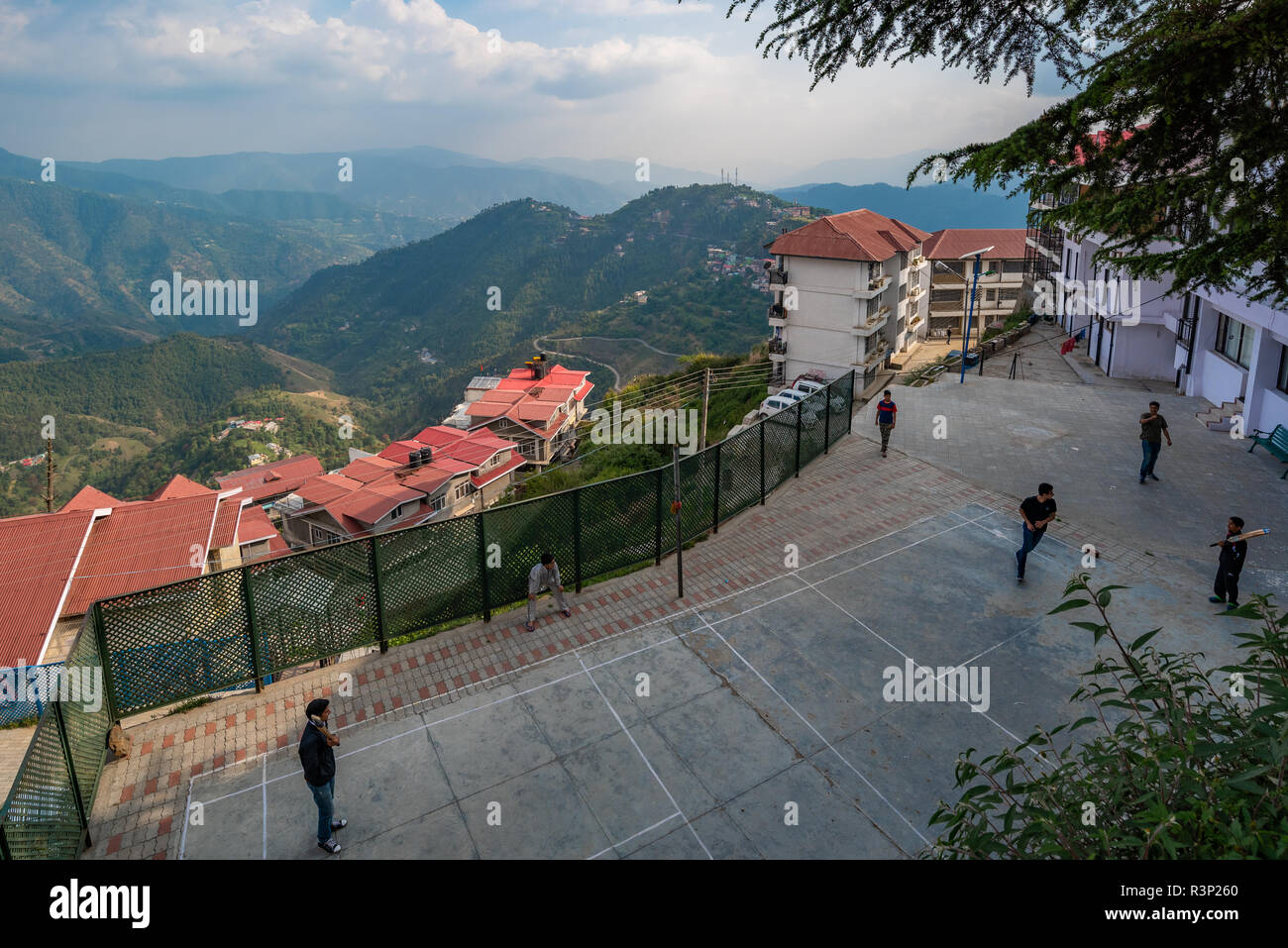 I ragazzi giocando una partita di cricket con il foothills dell'himalaya nel fondale in Kasumpti, Shimla, Himachal Pradesh, India Foto Stock