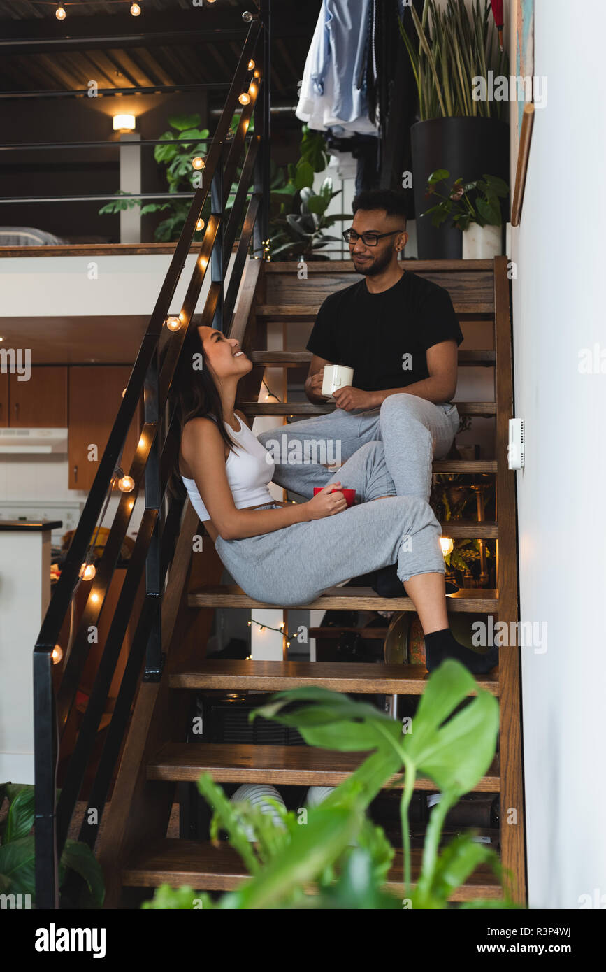 Paio di interagire gli uni con gli altri mentre un caffè in scale Foto Stock