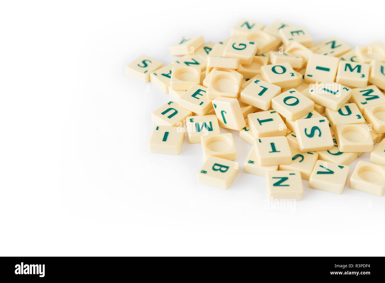 Pila di casuale gioco SCRABBLE lettera di piastrelle con valore di punteggio miscelati, isolati su sfondo bianco. Copia dello spazio. Foto Stock