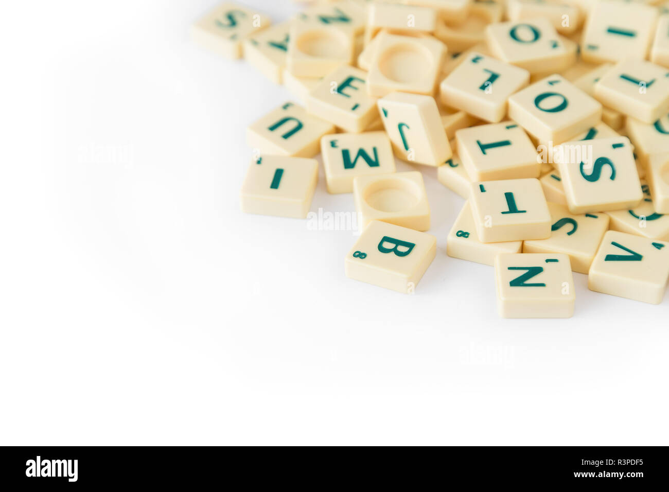Pila di casuale gioco SCRABBLE lettera di piastrelle con valore di punteggio miscelati, isolati su sfondo bianco. Copia dello spazio. Foto Stock