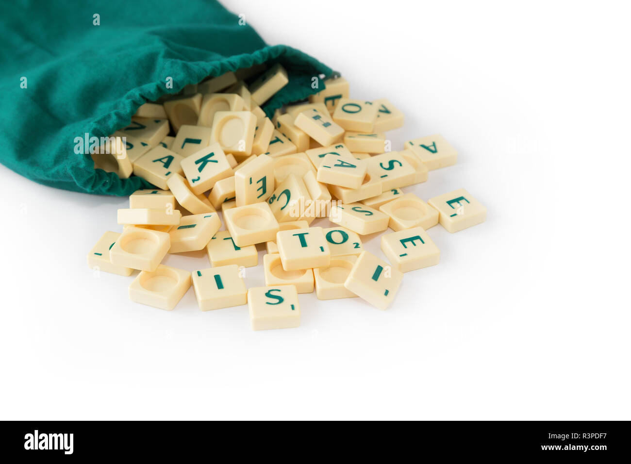 Random gioco SCRABBLE lettera di piastrelle con valore di punteggio proveniente dal loro verde borsa a cordoncino, isolato su sfondo bianco. Foto Stock