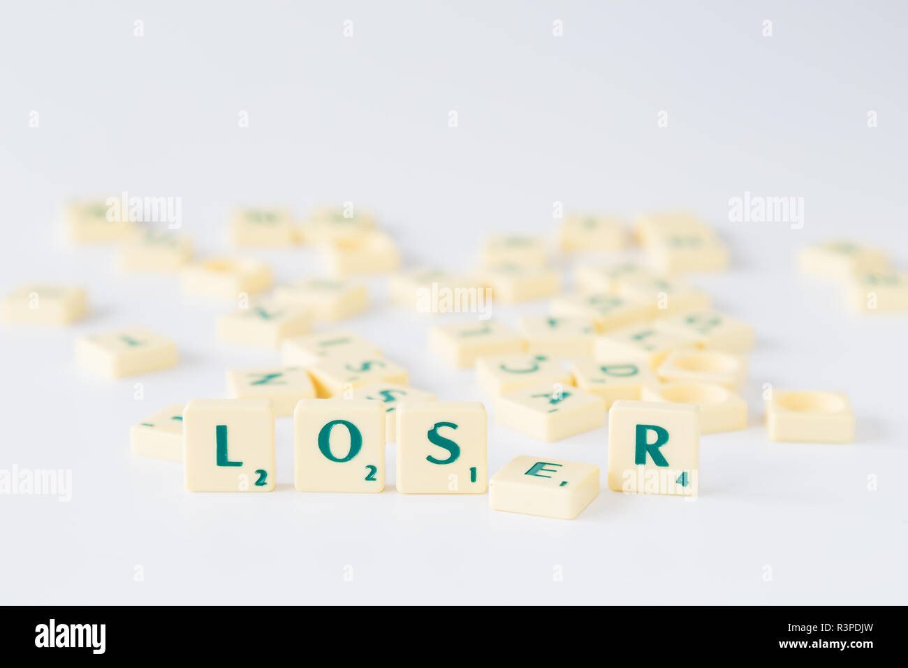 Focus sulla parola "perdente" fatta di gioco SCRABBLE lettera di piastrelle con valore di punteggio con la lettera E caduti. Piastrelle casuale miscelato fino in sfondo sfocato Foto Stock