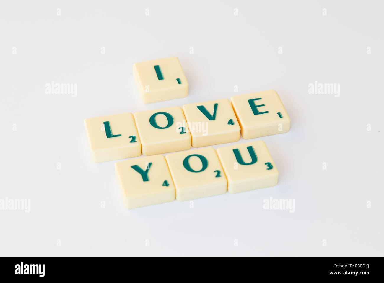 Gioco Scrabble lettera di piastrelle con valore di punteggio formando la frase "ti amo" su sfondo bianco. Foto Stock