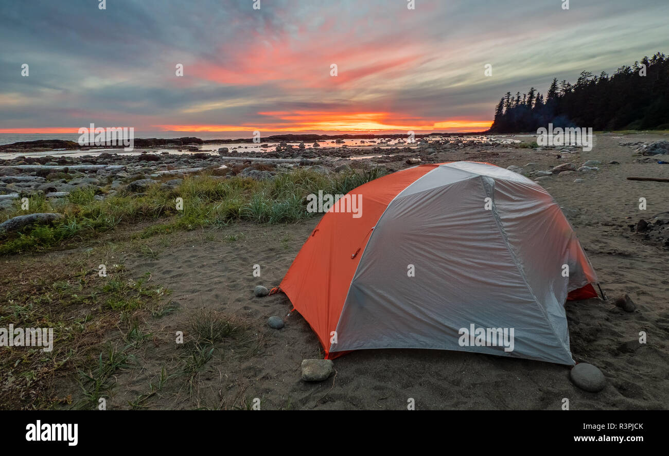 Backpacking tenda su una spiaggia con una straordinaria drammatica sunrise in distanza. Foto Stock