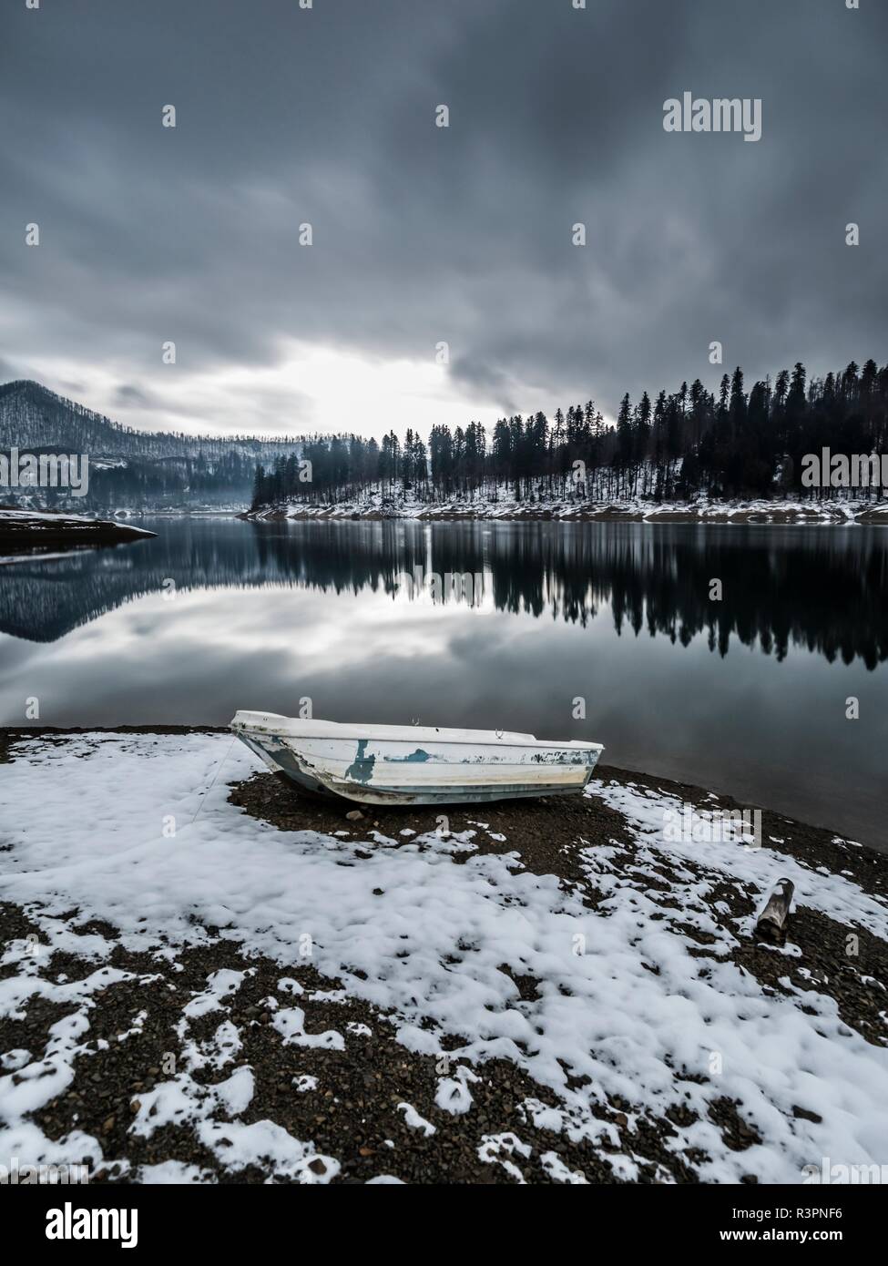 Una lunga esposizione inizio inverno neve in Europa Croazia Lokve lago di destinazione una barca che giace a terra ormeggiato con fune Foto Stock
