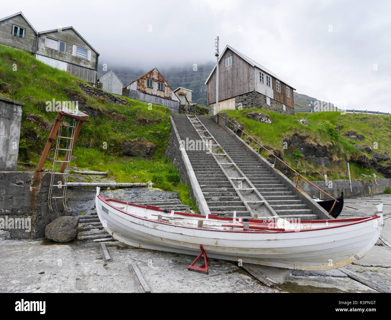 Jetty di villaggio Kunoy. Le imbarcazioni sono redatti al boatsheds utilizzando l'uno scalo. Isole Faerøer, Danimarca Foto Stock