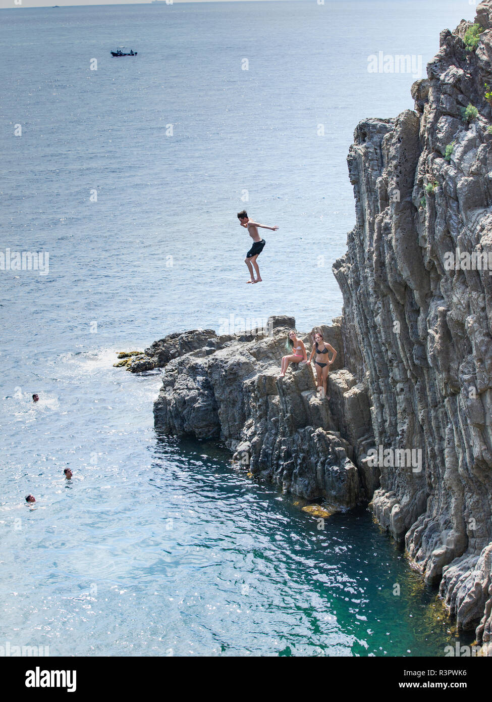 Teens high diving di ocean cliff Foto Stock