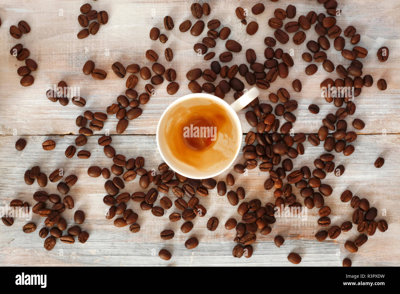 Tazza vuota con resti di caffè espresso e caffè torrefatto in grani su legno Foto Stock