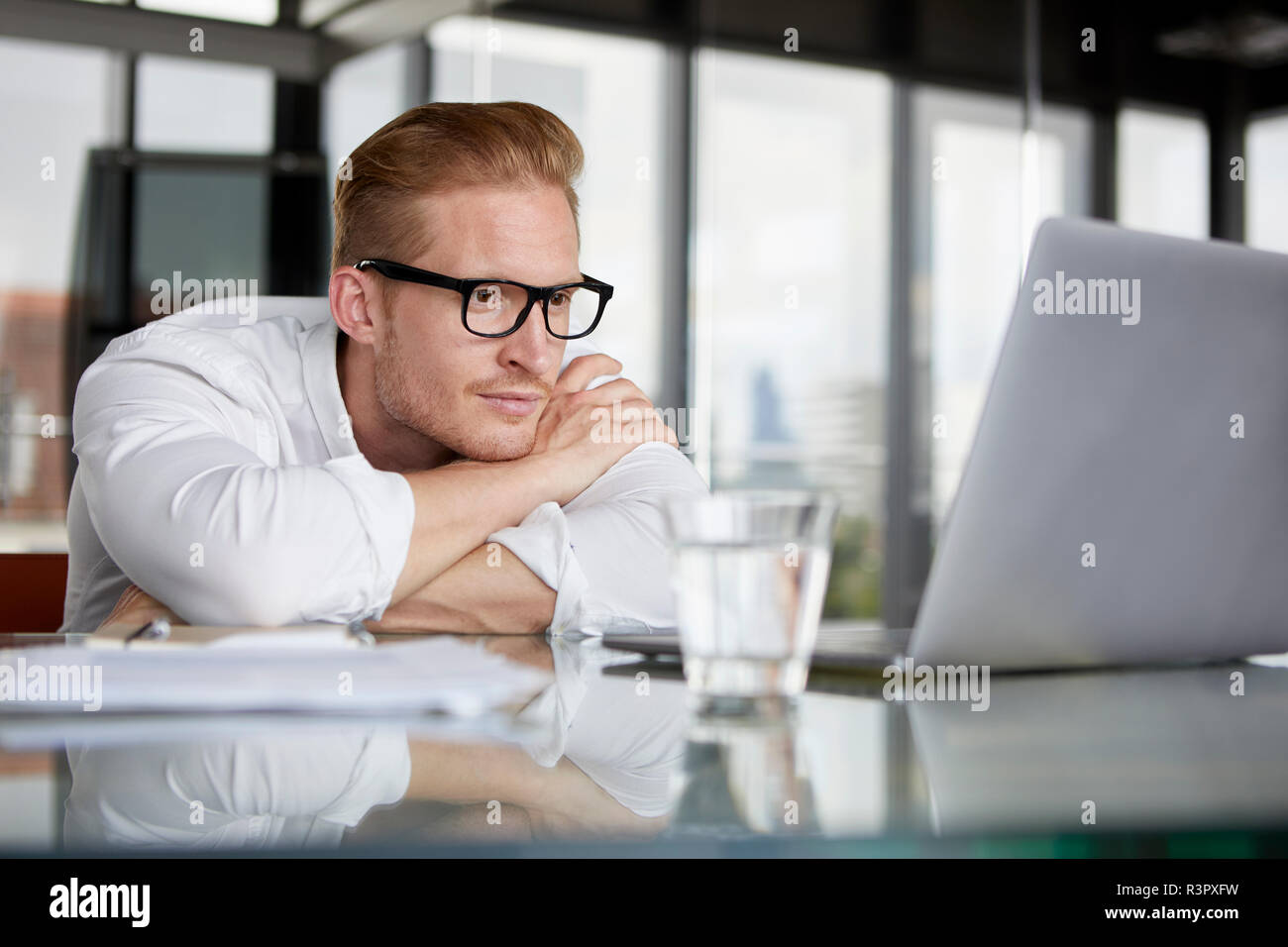 Imprenditore appoggiato sulla scrivania in ufficio con computer portatile Foto Stock