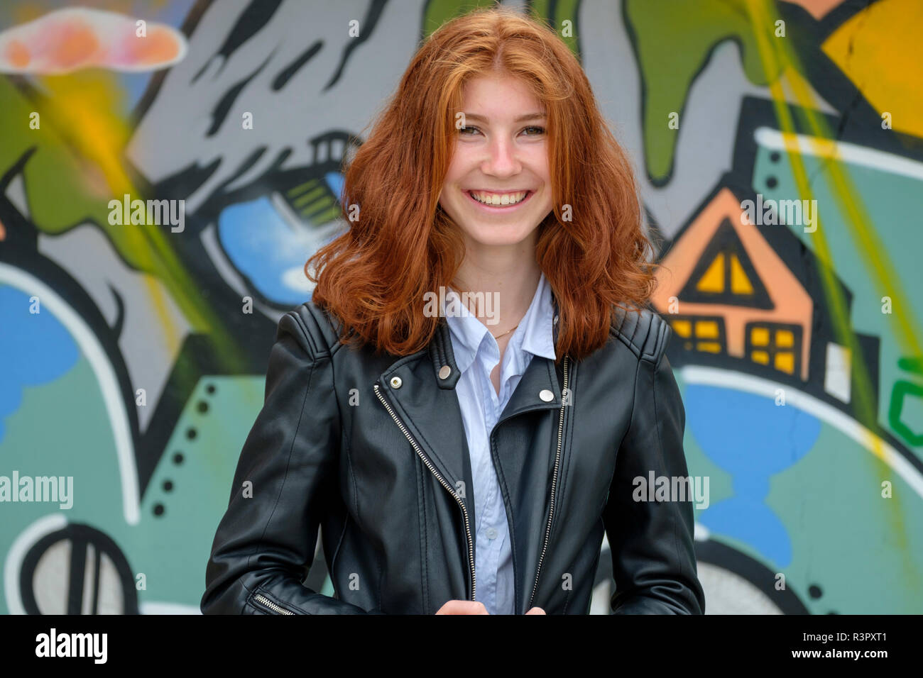 L'Italia, Finale Ligure, ritratto di ridere redheaded ragazza adolescente nella parte anteriore del murale Foto Stock