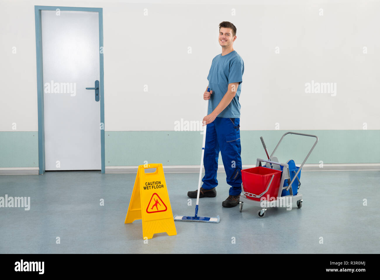 Lavoratore di sesso maschile con attrezzature di pulizia pavimento con straccio Foto Stock