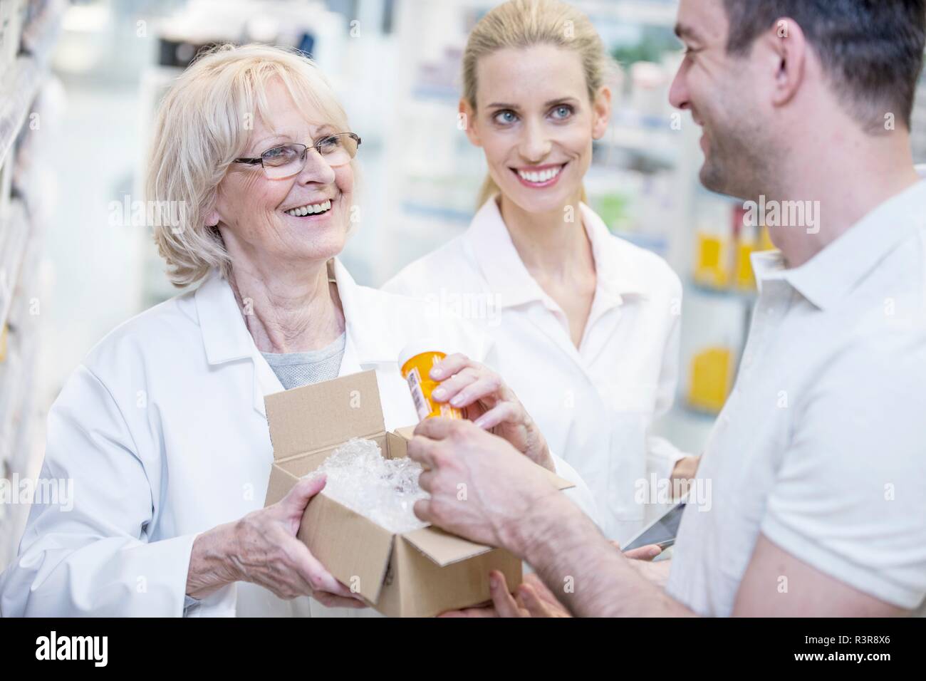 Il farmacista di prendere la pillola bottiglia da una scatola e consegnarla al cliente. Foto Stock